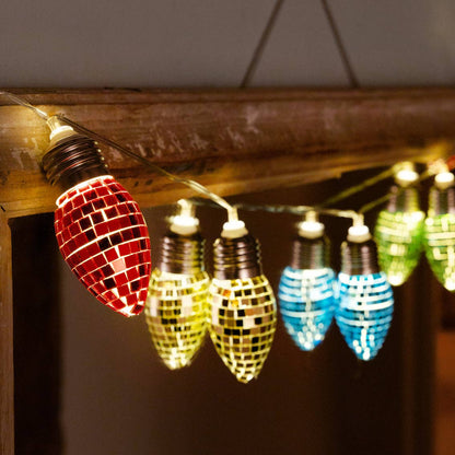 Close-up of lit mirror-tile bulbs in red, yellow and blue glowing along a wooden mantel