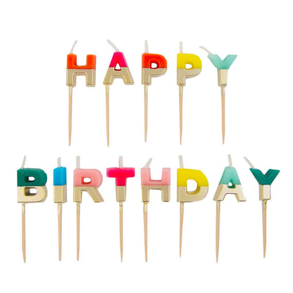 Thirteen rainbow letter candles dipped in gold, spelling Happy Birthday on two rows