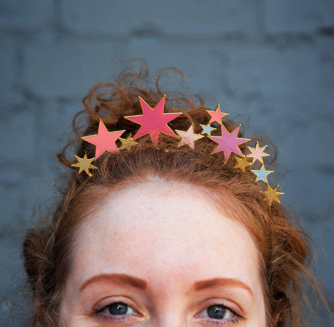 Close-up of a woman wearing the star headband on her curly red hair
