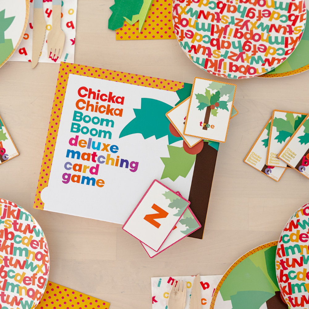 Matching card game box with letter and tree cards fanned out beside alphabet-print plates