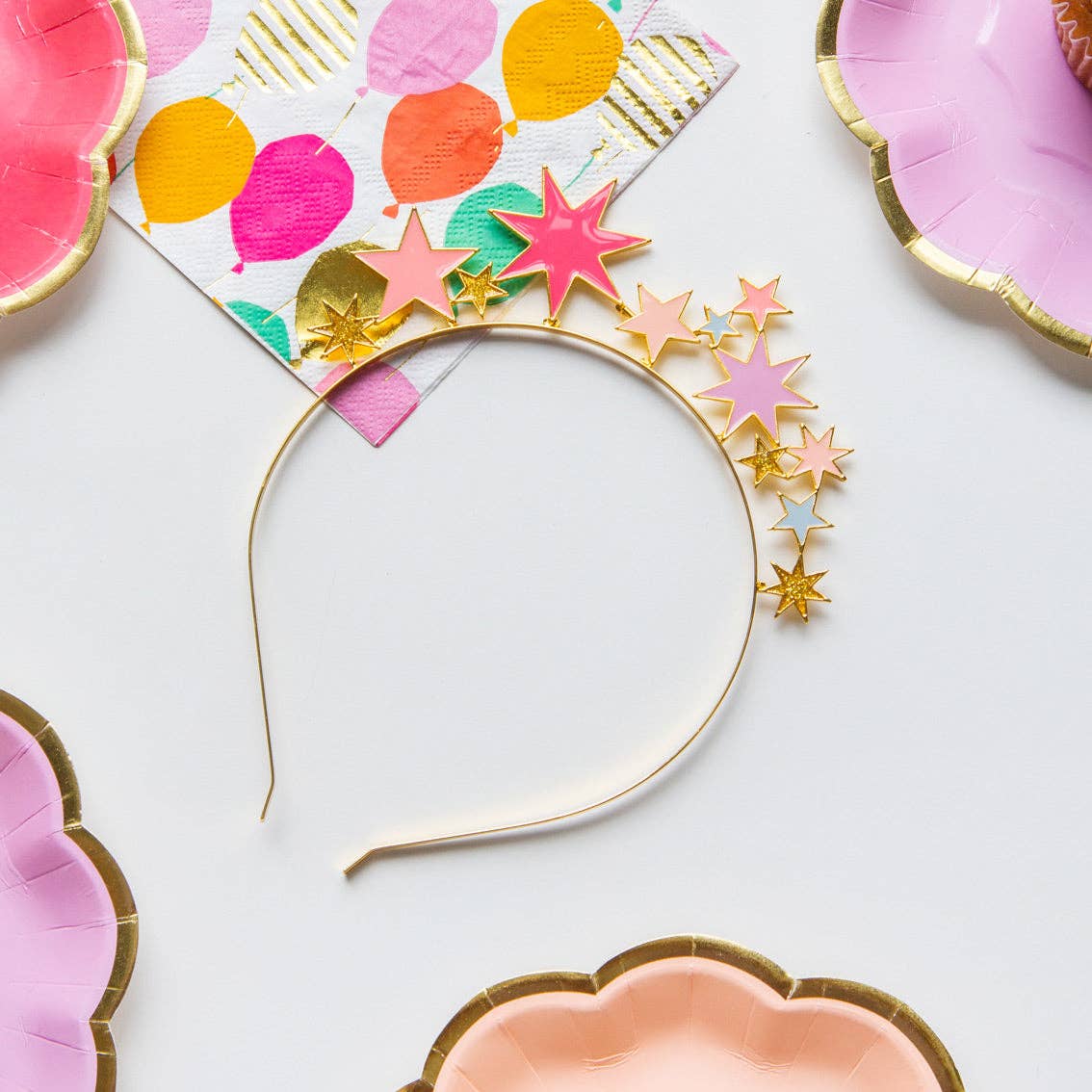 Star headband flat on a table among colorful party plates and a balloon-print napkin