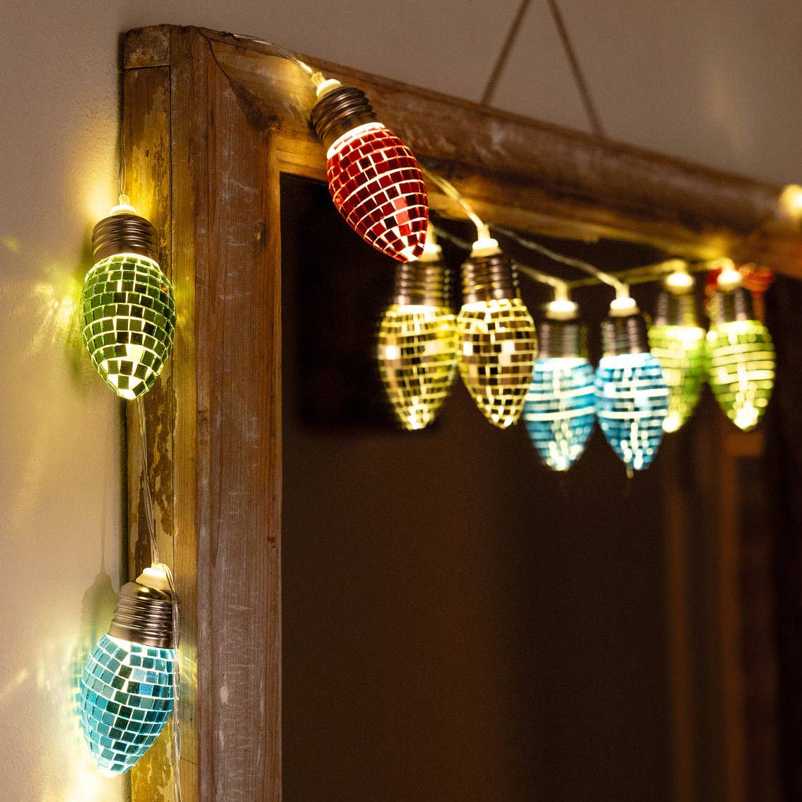 String of lit disco bulbs in green, yellow and blue draped around a wooden frame