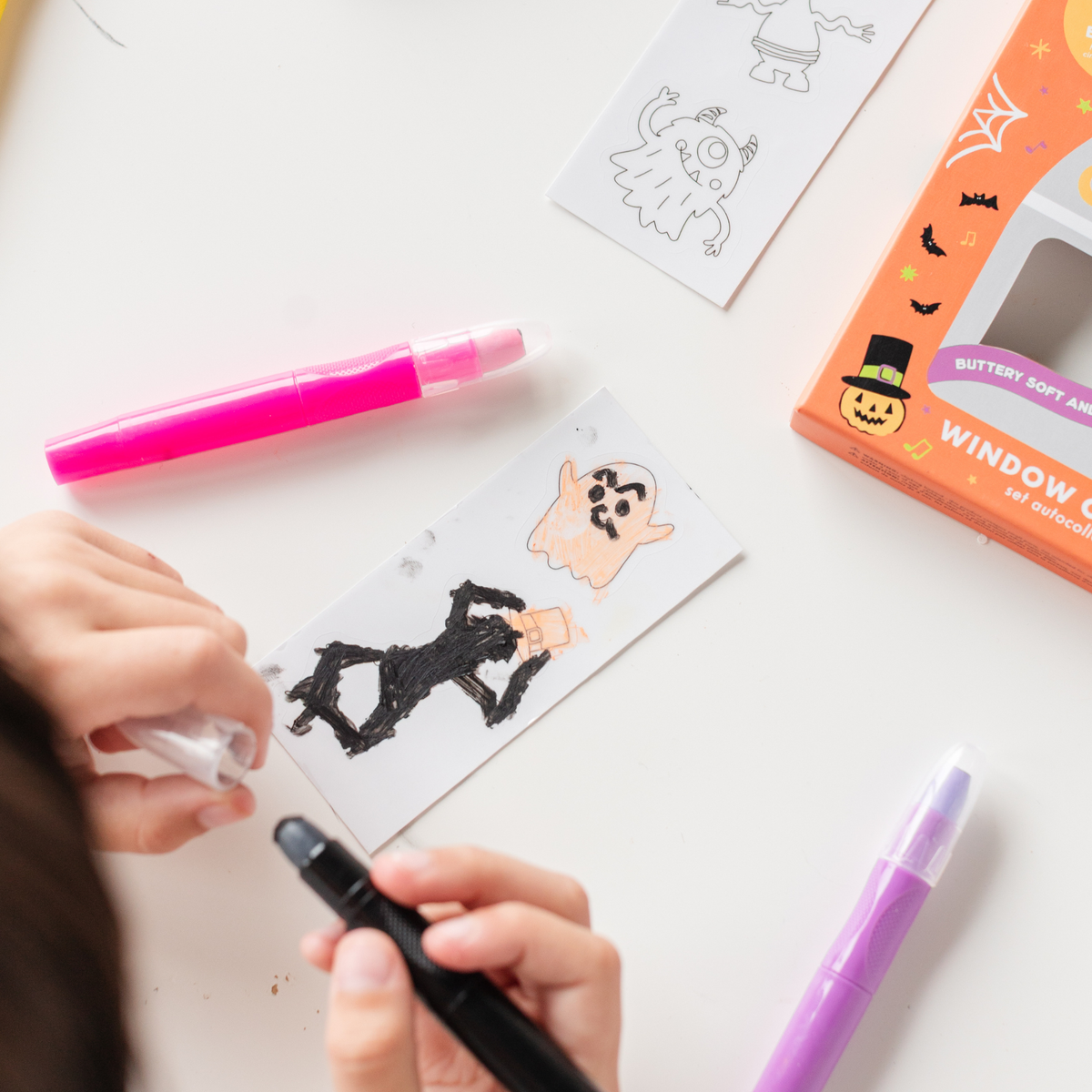 Child coloring a black and white monster cling with window crayons