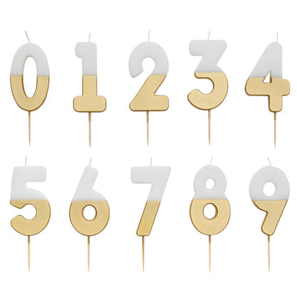 White and gold dipped number candles from 0 to 9 laid out in two rows