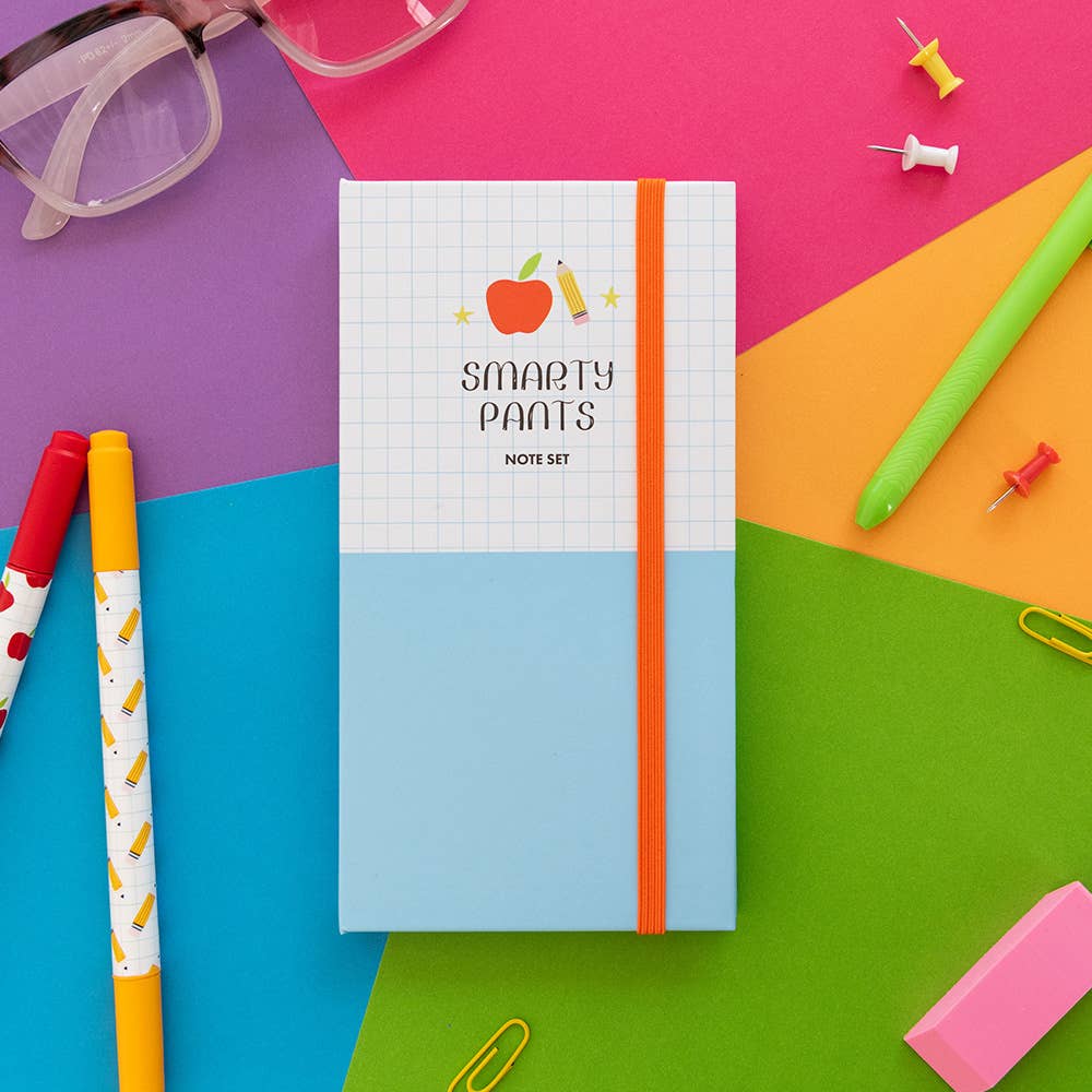 Closed Smarty Pants note set on a bright desk with pens, paper clips and an eraser