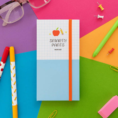 Closed Smarty Pants note set on a bright desk with pens, paper clips and an eraser